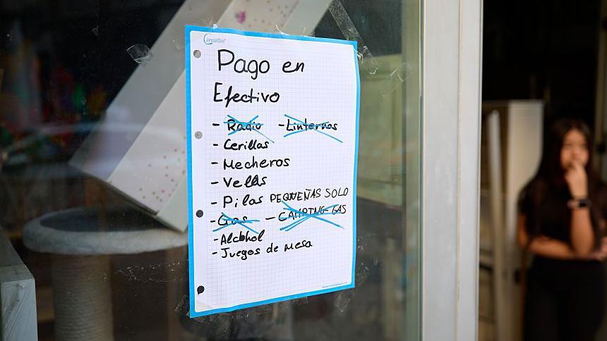 Un cartel en una tienda muestra la lista de cosas y pide pago solo en efectivo.