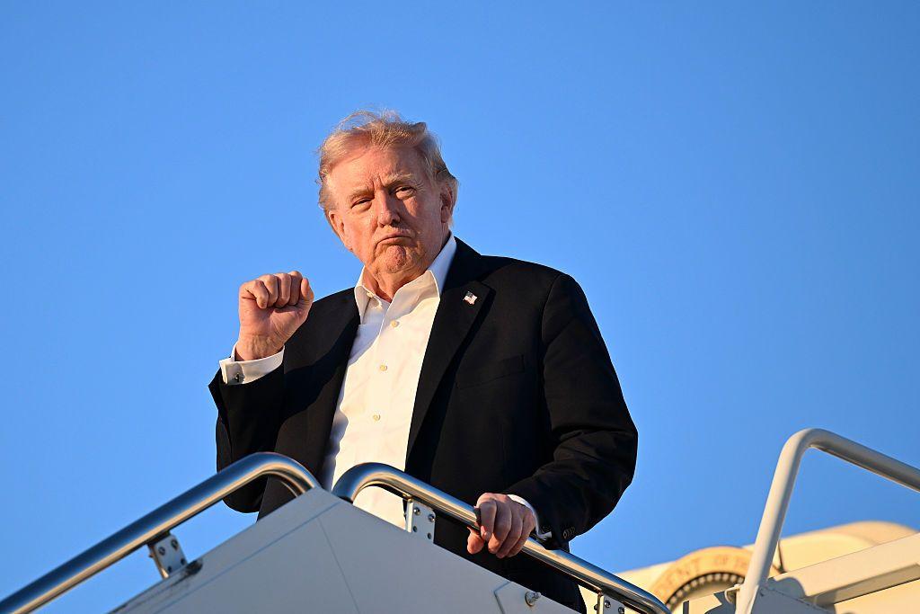 Trump saindo do avi&atilde;o e fazendo um gesto com os punhos fechados