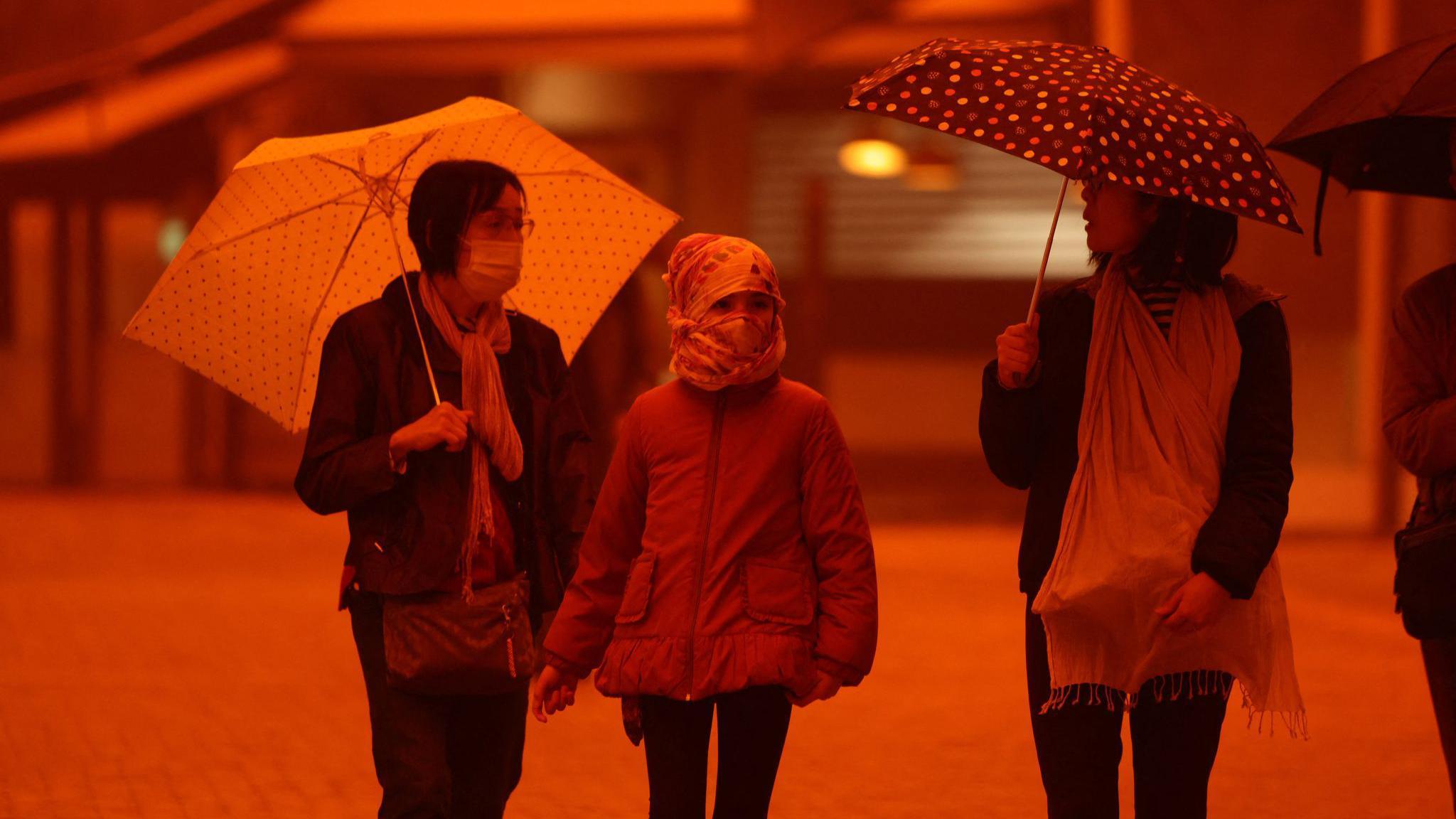 Dve žene i devojčica hodaju usred izmaglice izazvane peščanom prašinom iz Sahare, usled jakih južnih vetrova, u Iraklionu, na ostrvu Krit noseći kišobrane i maske za lice