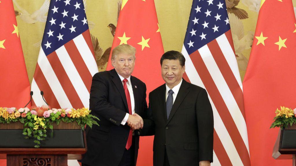 特朗普與習近平在一排捲起的中美國旗前握手。