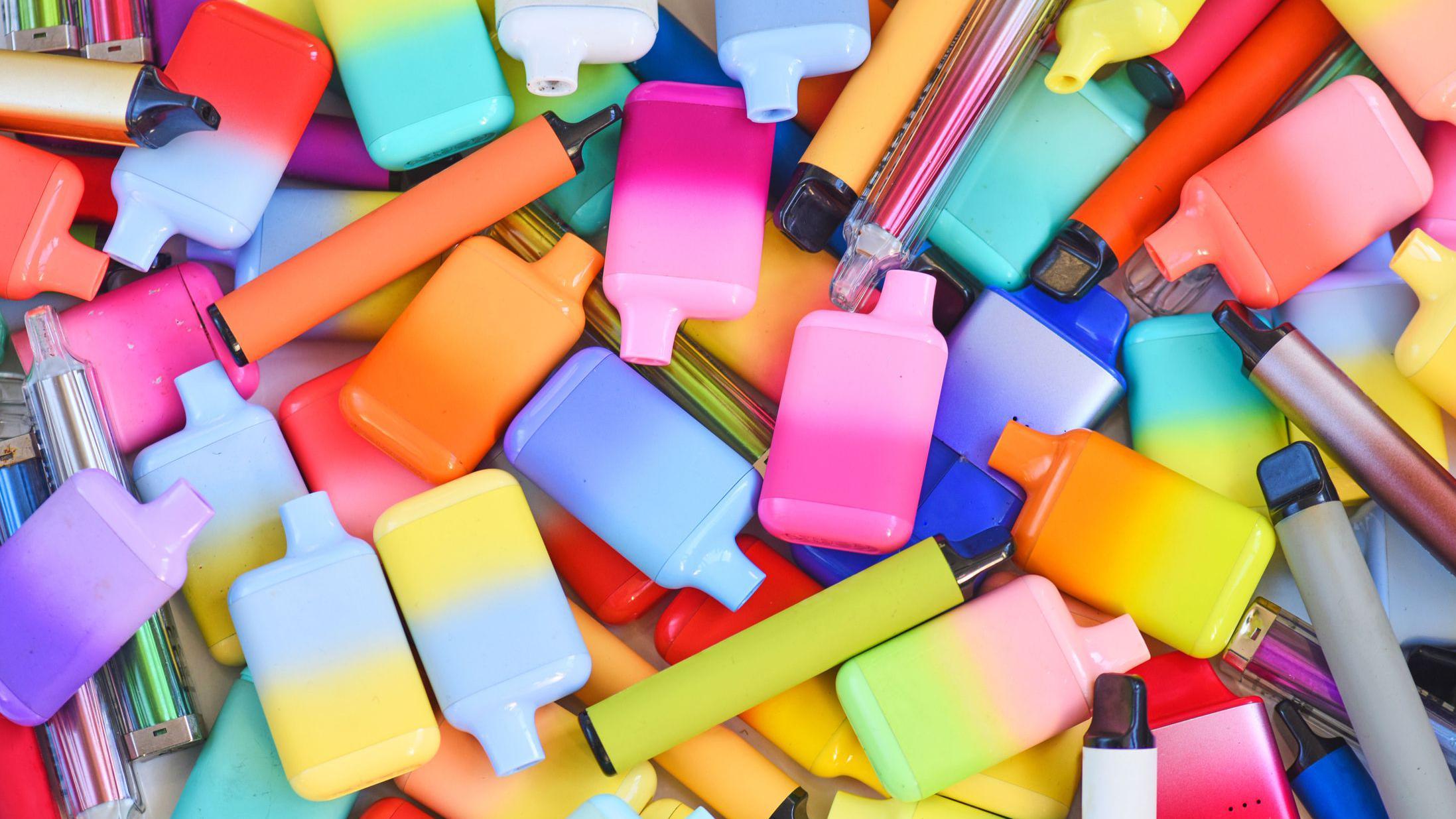 Uma foto de vários vapes coloridos e brilhantes, de diferentes formatos e tamanhos.