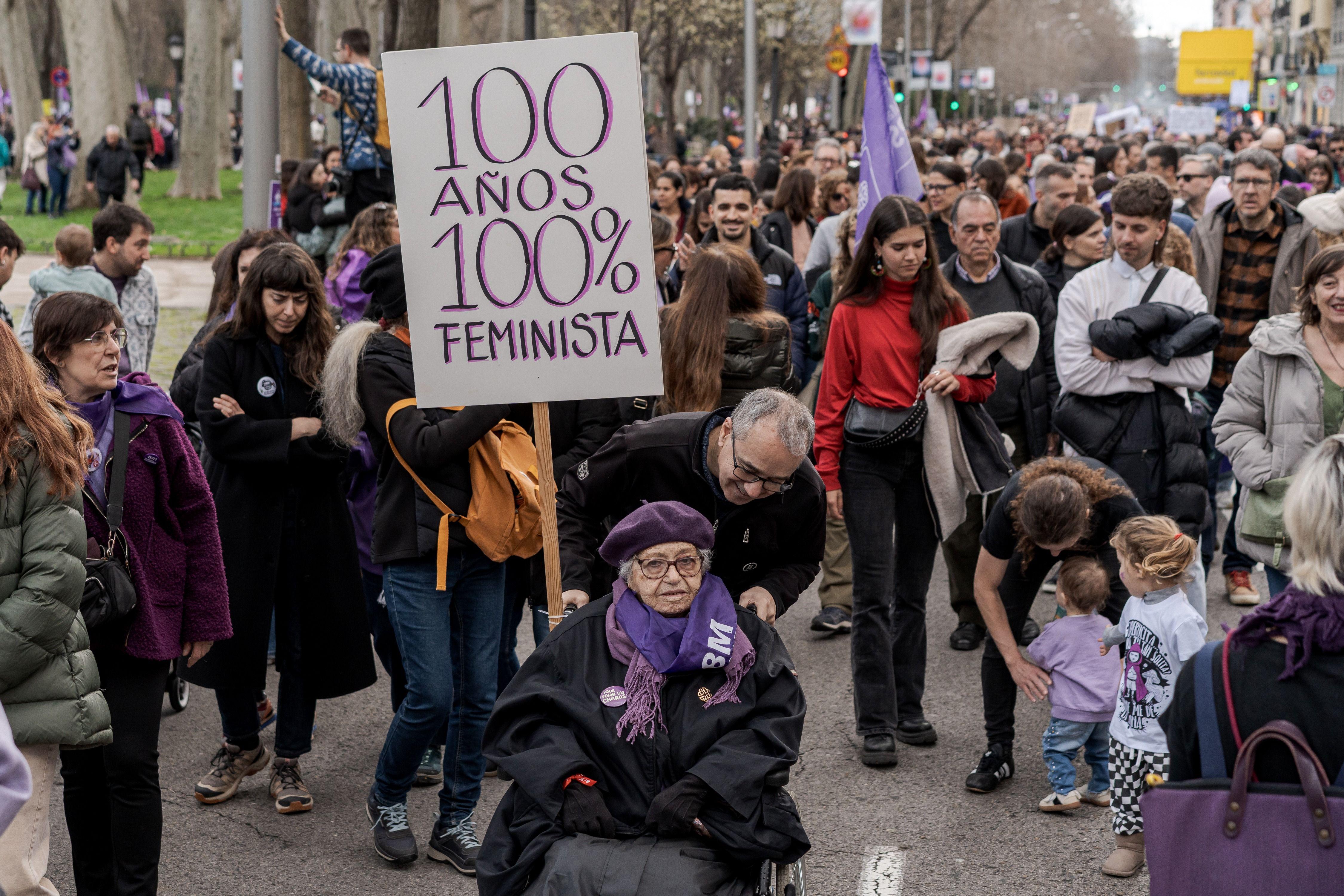 Persona portando una pancarta con el lema "100 años, 100 % feministas".