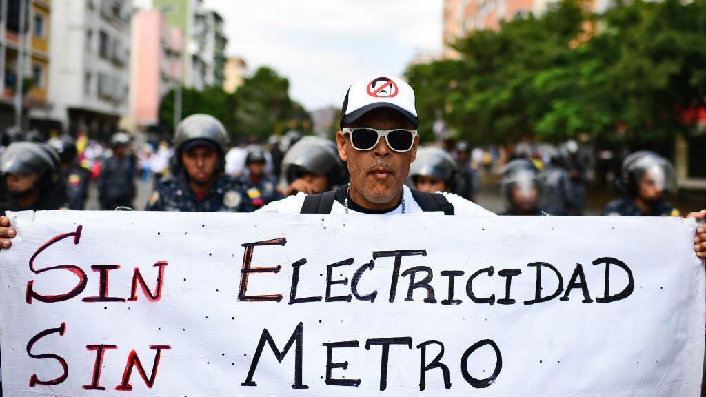 Manifestante protesta em Caracas com um cartaz dizendo 'Sem eletricidade, sem metr&ocirc;'