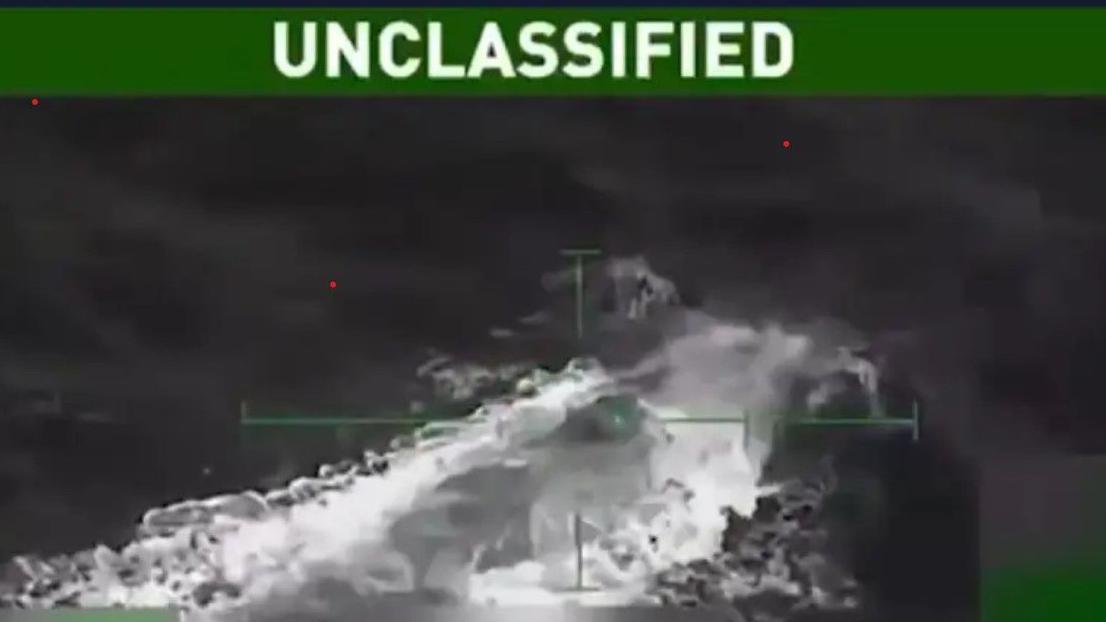 Imagen difuminada en blanco y negro en la que se percibe una especie de submarino que empieza a reflotar en el mar.