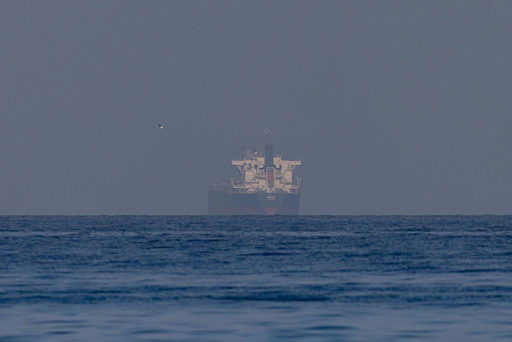 Un barco de carga, visto en la distancia navegando en un día soleado por el estrecho de Ormuz. 