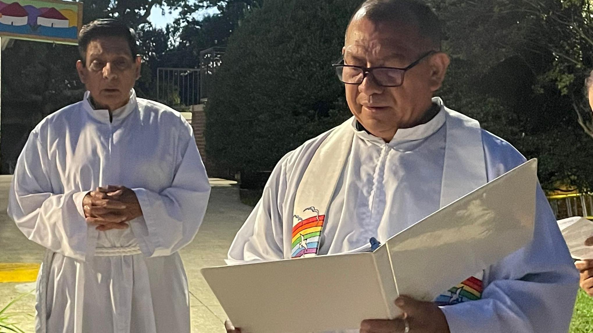 El padre Vidal Rivas (derecha), párroco de San Mateo, en Hyattsville, Maryland, lee durante en festival de San Francisco de Asís junto a otro sacerdote.