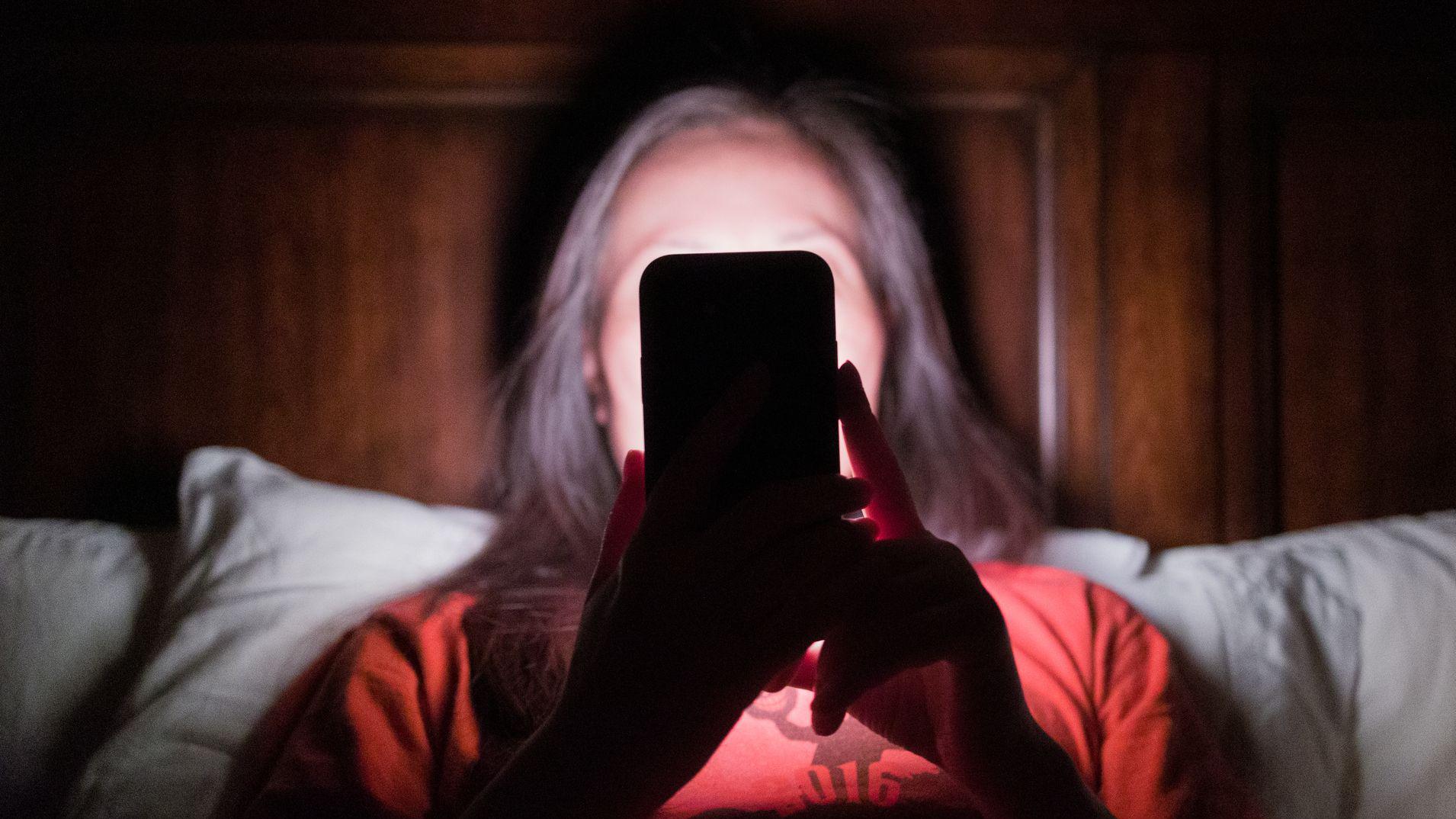 Mujer mirando el celular en la cama