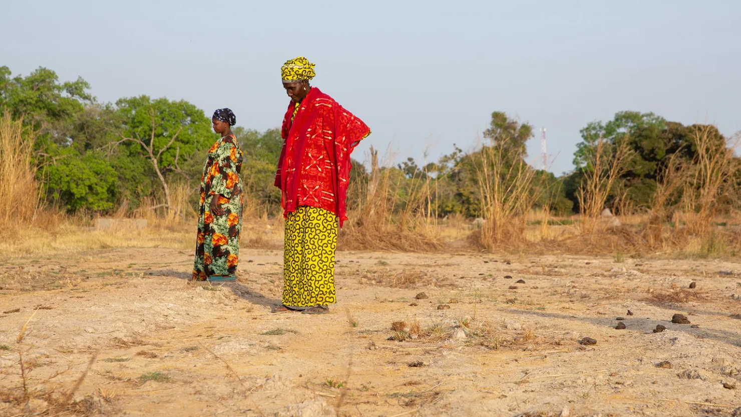 Dos mujeres en Gambia miran hacia el suelo. Antes podían cultivar arroz ahí, pero ya no. 