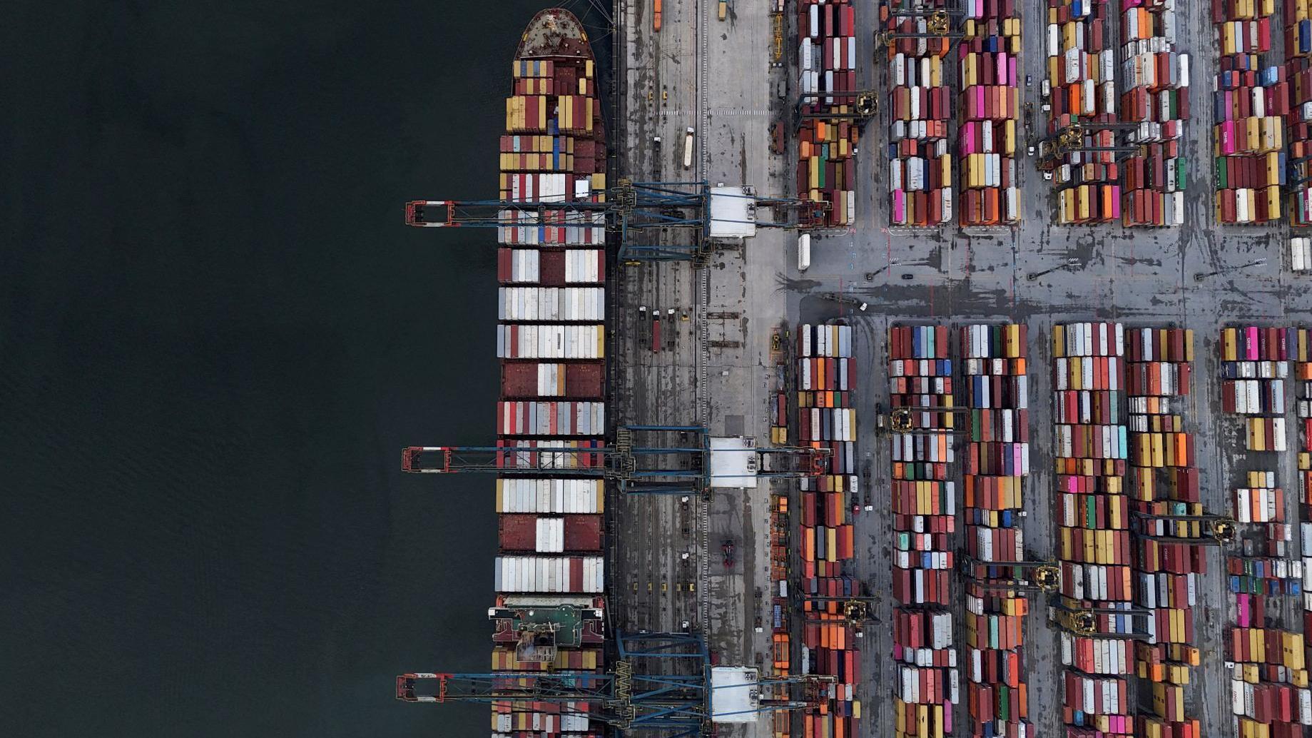 O porto de Santos visto de cima, com um navio e centenas de contêiners coloridos. 