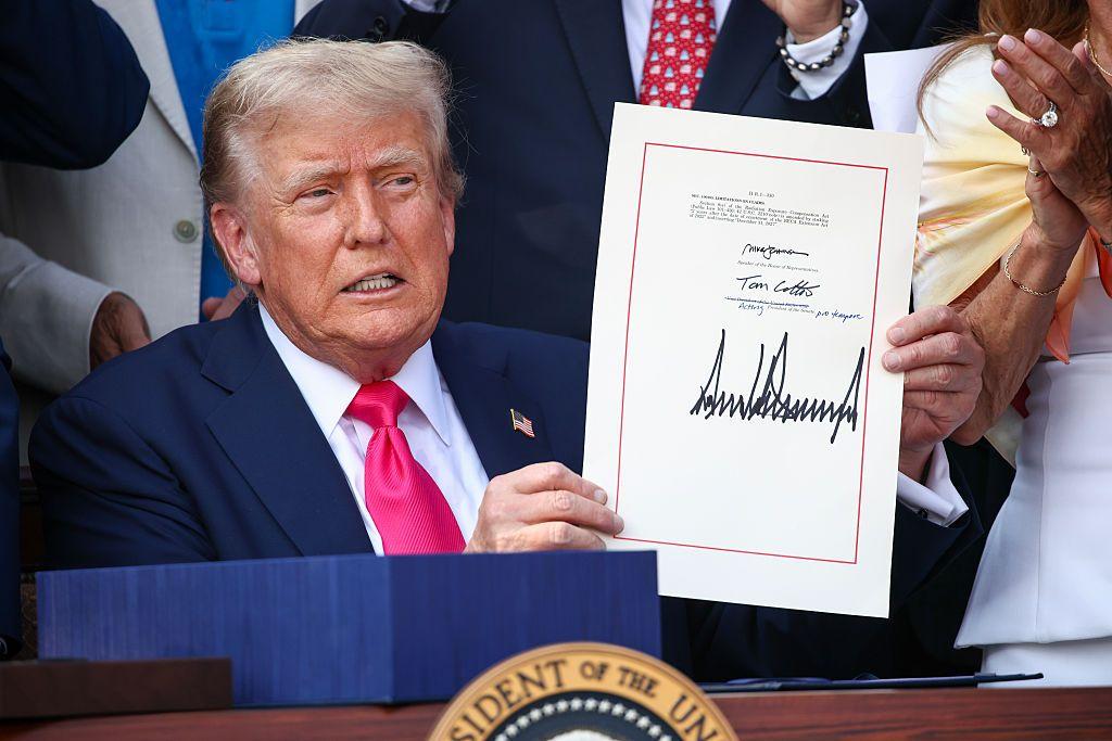 El presidente estadounidense Donald Trump, acompañado de legisladores republicanos, sostiene el acta del Gran y Hermoso Proyecto de Ley durante un picnic militar familiar del Día de la Independencia en el Jardín Sur de la Casa Blanca el 4 de julio de 2025 en Washington, DC. (Foto: Samuel Corum/Getty Images) 