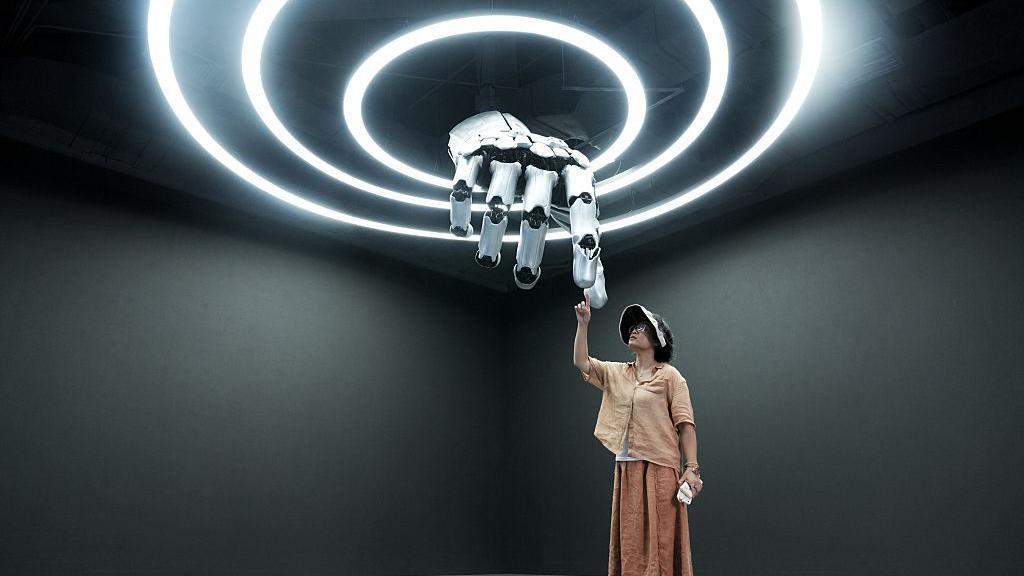 2025年8月4日，在位於中國北京亦莊的「機器人商城」——全球首家具身智能機器人4S店，一名參觀者正在與機械手互動。該設施計劃於2025年世界機器人大會期間（8月8日至12日）在北京南部亦莊的機器人產業園內開業。