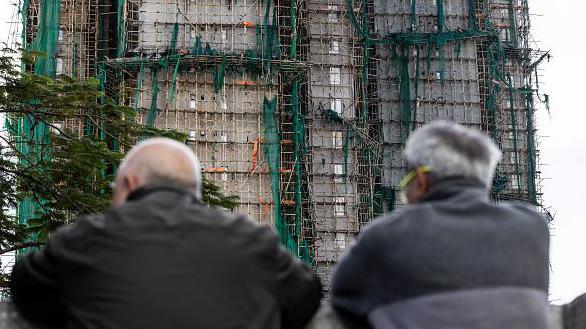 香港大埔區宏福苑住宅大樓發生火災，損毀嚴重。兩名頭有白髮的男子看著樓宇。