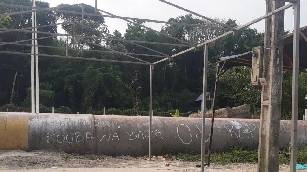 'Rouba na baixa C.V' escrito em cano, perto de mata