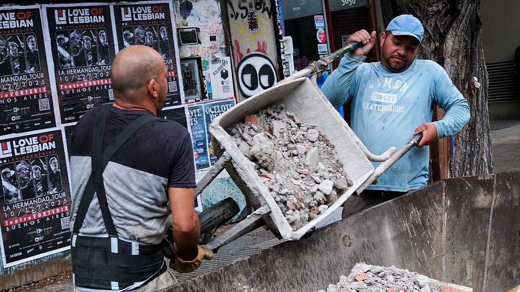 Trabajadores de la construcción vacían una carretilla en un contenedor el 24 de octubre de 2025, Buenos Aires, Argentina.