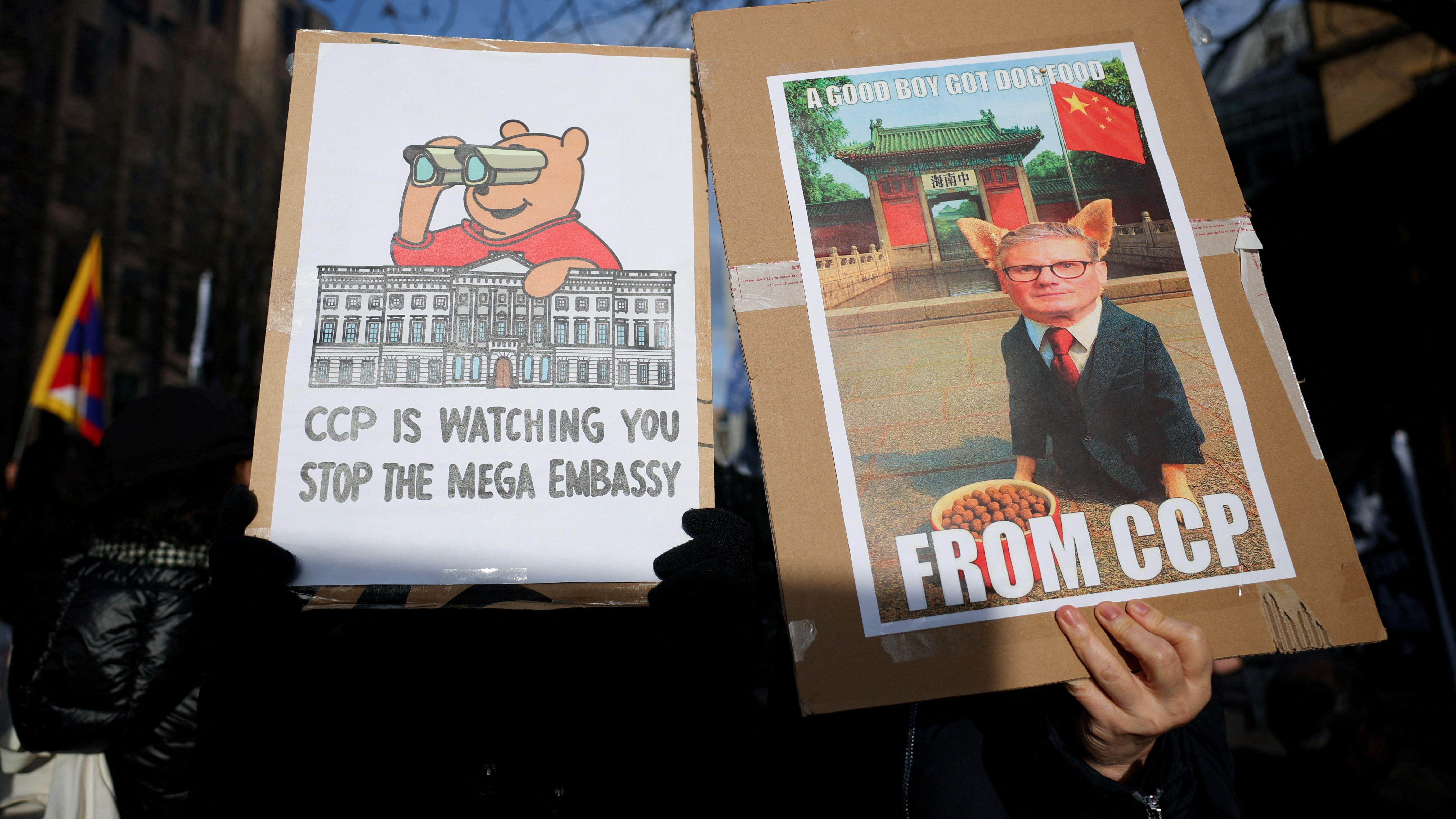 英國倫敦皇家造幣廠原址附近一群抗議建設中國「超級大使館」的示威者舉起標語牌，其中左邊諷刺施紀賢爵士刻意跟中共「討狗糧」（17/1/2026）