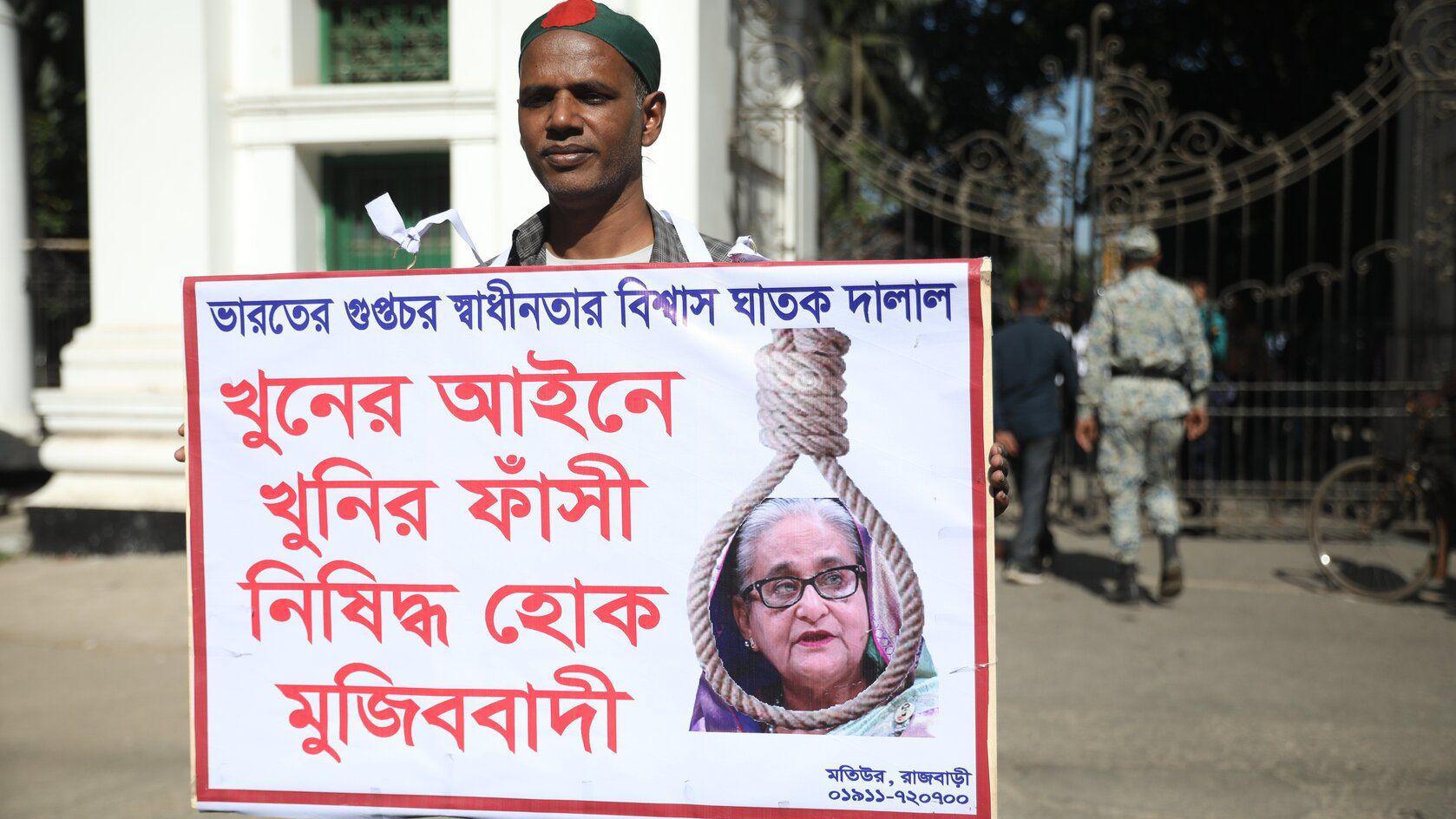 Muškarac drži u ruci transparent na kojem je slika bivše premijerke Šeike Hasani