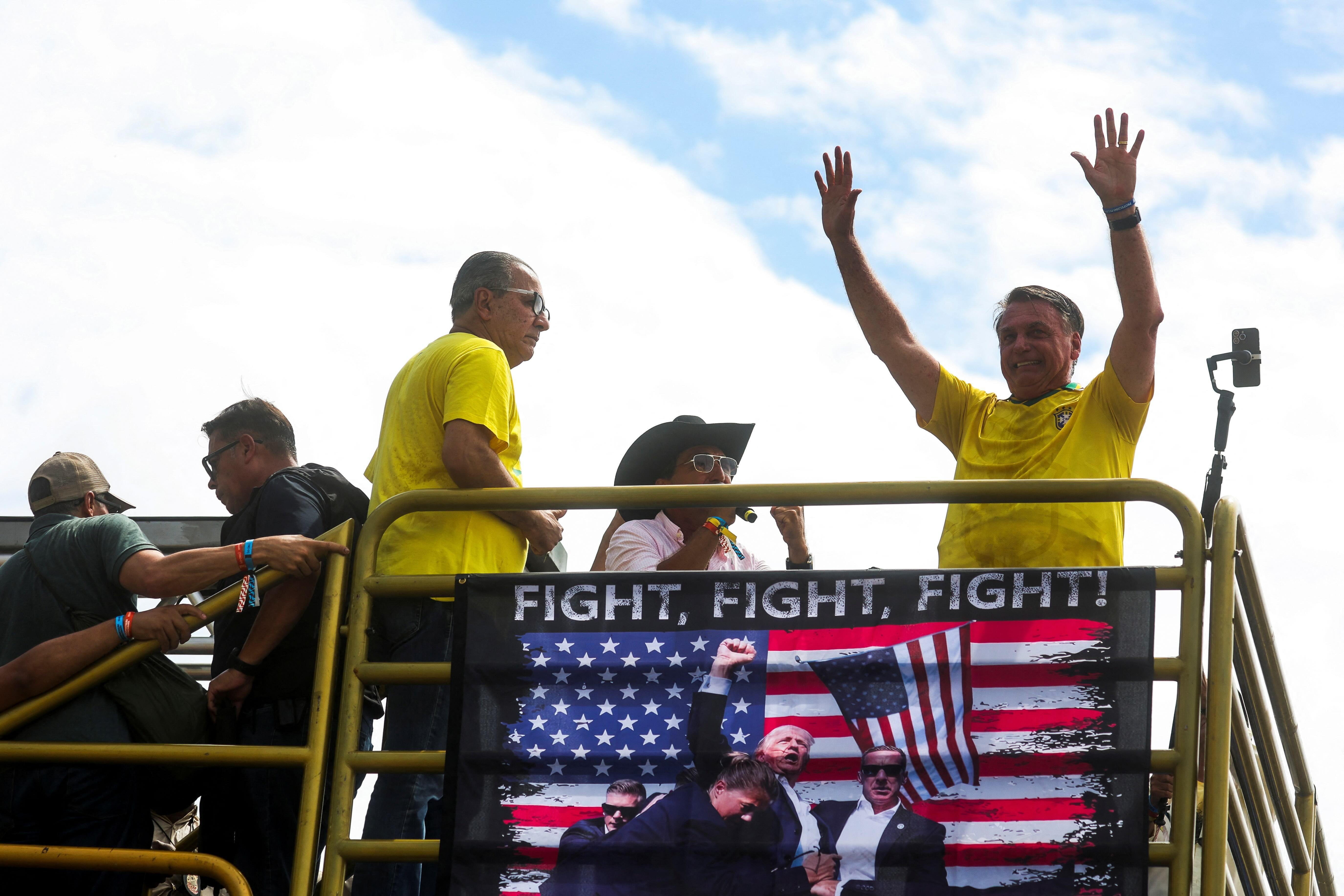 Jair Bolsonaro en una manifestación con una imagen de Trump sosteniendo una bandera de EE.UU.