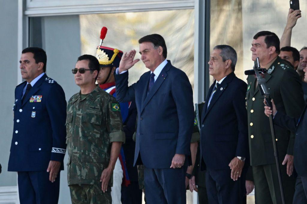 Bolsonaro faz contin&ecirc;ncia durante evento. Ao lado dele h&aacute; v&aacute;rios militares