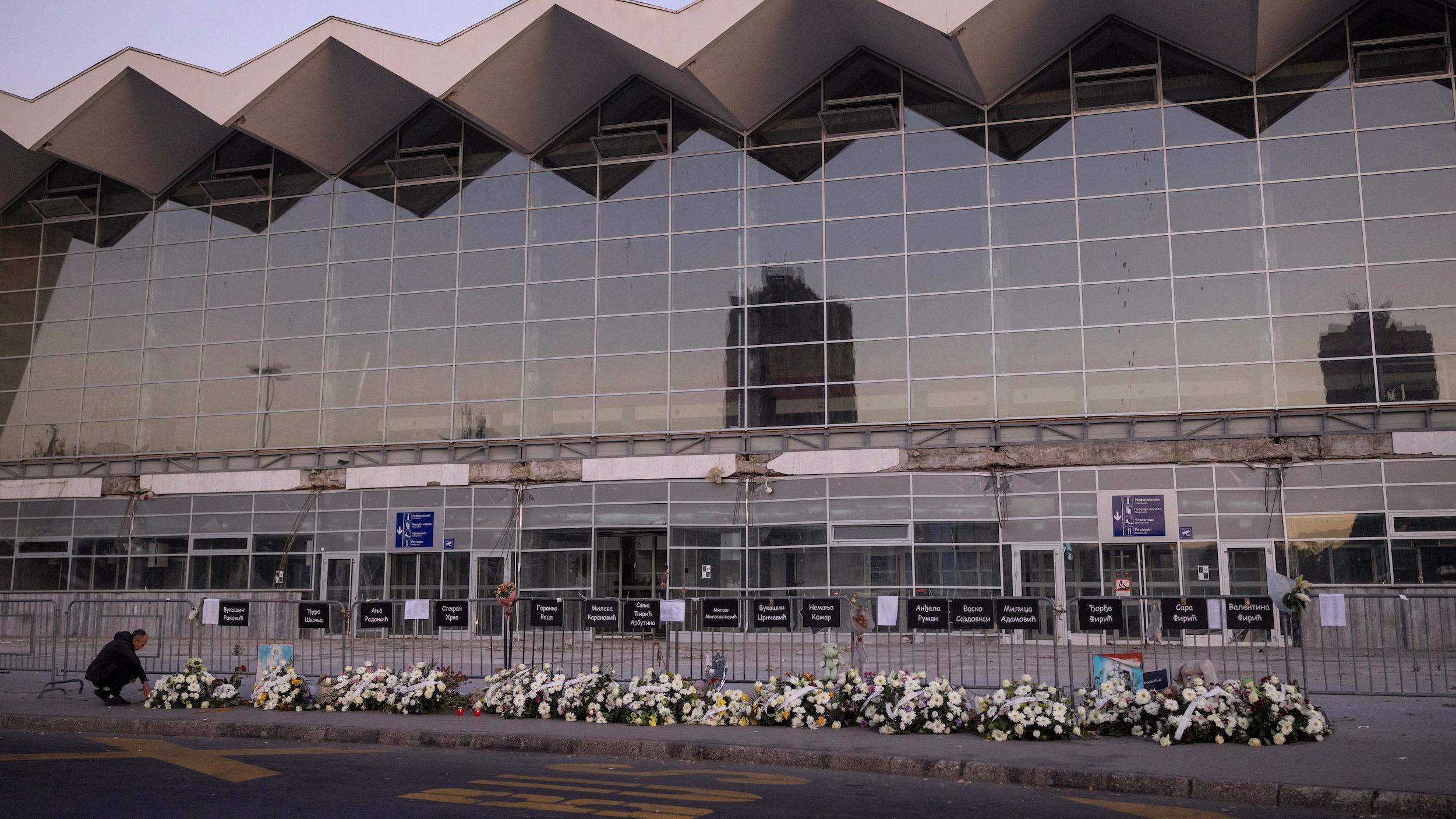 Venci i cveće za nastradale ispred zgrade Železničke stanice u Novom Sadu, muškarac u levom uglu ostavlja cveće
