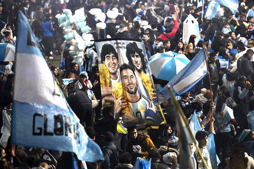 Hinchas argentinos sostienen una pancarta con las imágenes de los futbolistas campeones del mundo Diego Maradona, Mario Kempes y Lionel Messi cerca de la concentración de la Asociación del Fútbol Argentino (AFA) en Ezeiza, Buenos Aires, el 20 de julio de 2026.