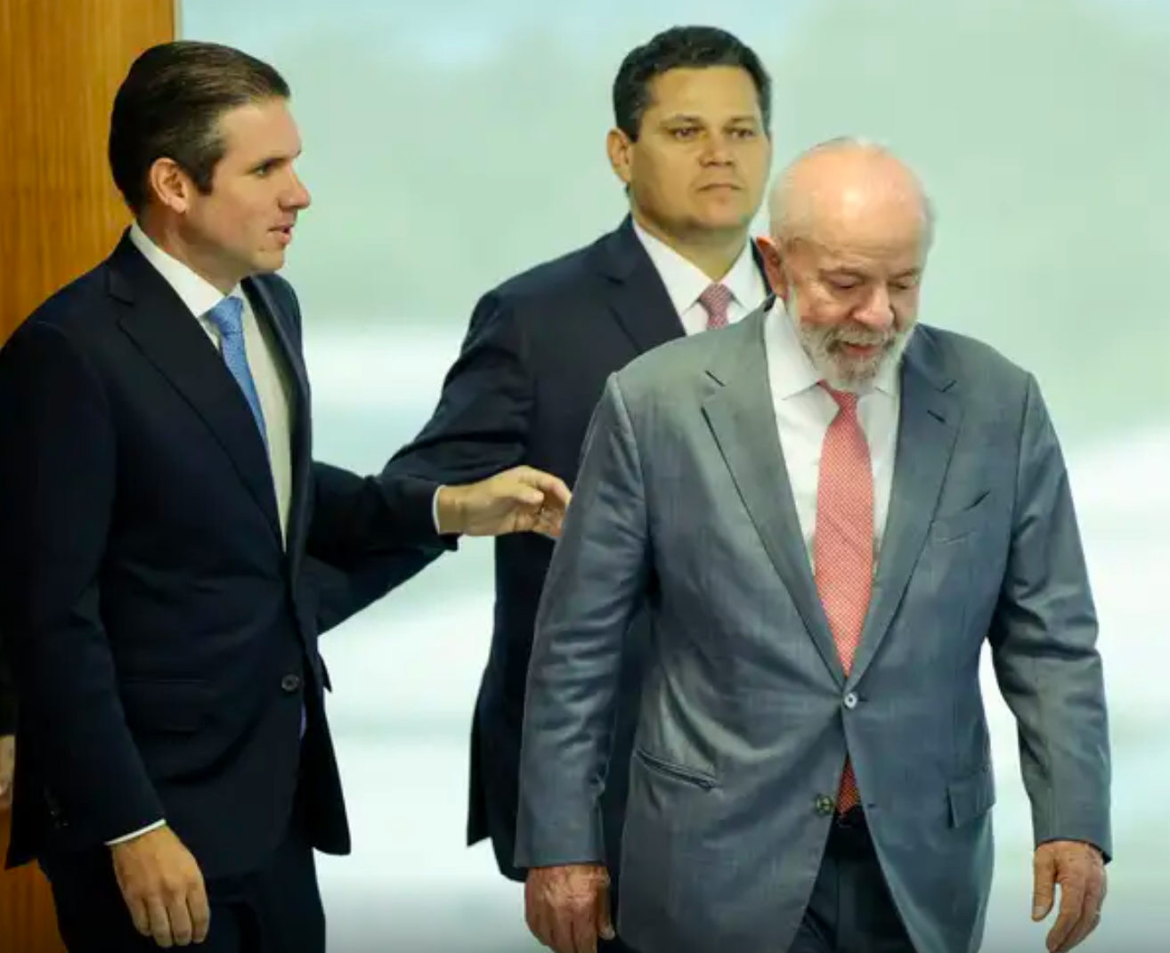 Foto mostra o presidente da C&acirc;mara dos Deputados, Hugo Motta, &agrave; esquerda, o presidente do Senado, Davi Alcolumbre, &agrave; direita, e Lula a frente dos dois. Lula olha para o ch&atilde;o enquanto os dois acompanham o presidente. Todos usam terno