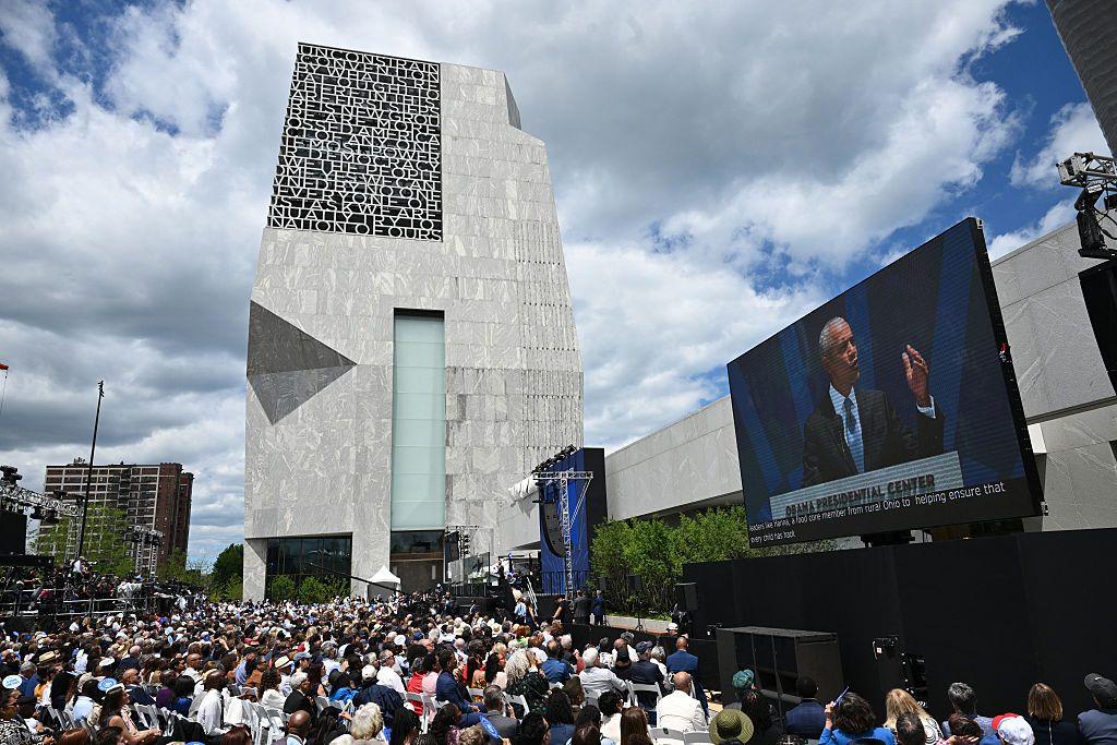 Obama dando su discurso frente a la torre del Centro. Hay una multitud escuchándolo y se ve al expresidente en una gran pantalla.