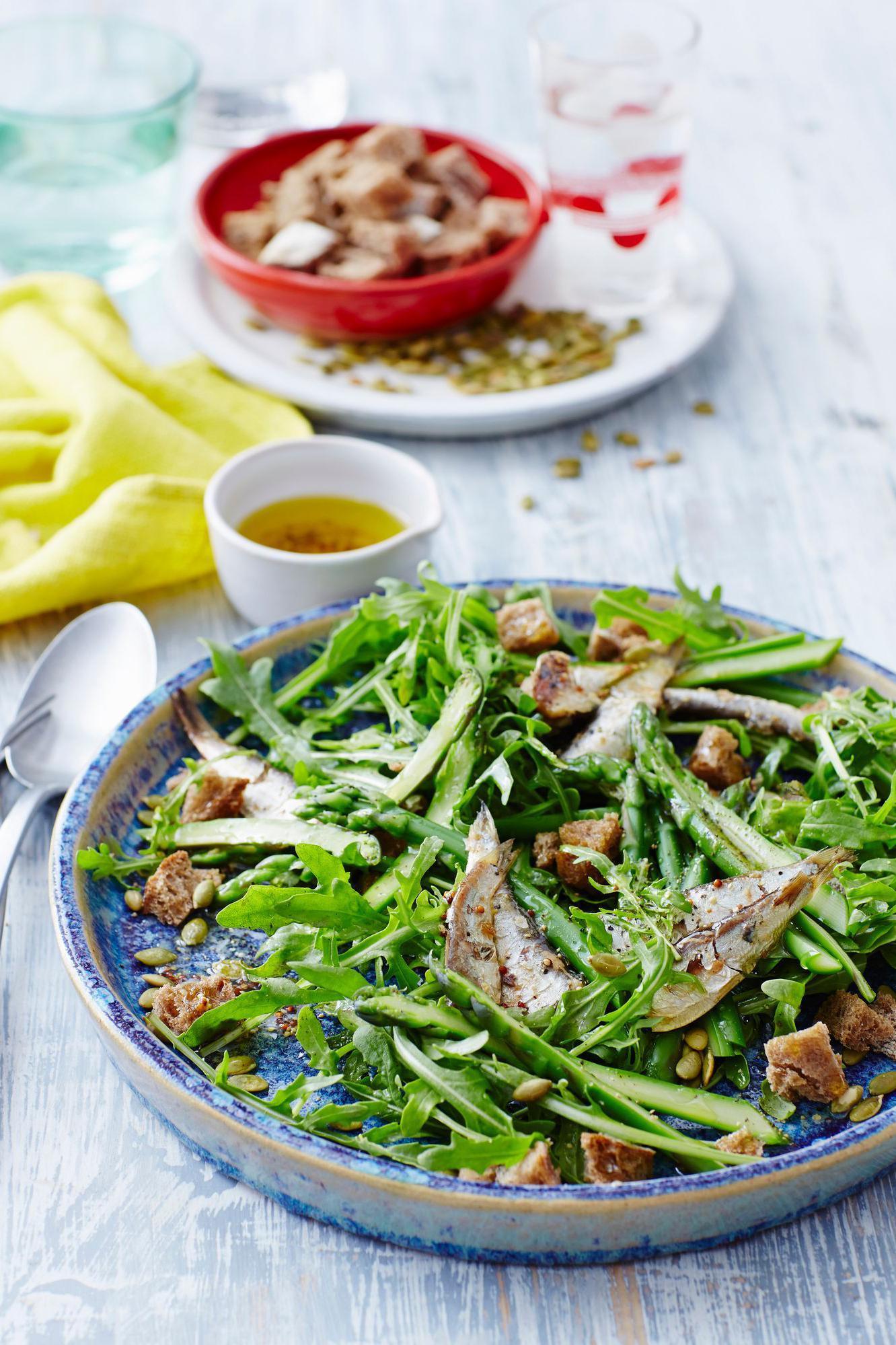 Salada com sardinhas e croutons, servida em um prato azul