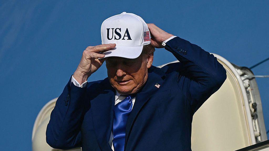 O presidente dos Estados Unidos, Donald Trump, ajusta boné onde se lê 