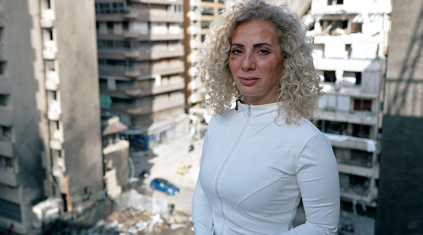 امرأة تقف على شرفة مطلة على موقع تفجير
