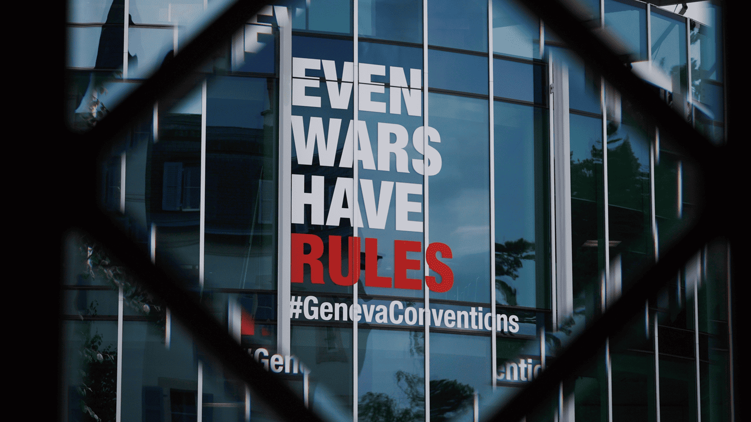 Sinal dizendo, em ingl&ecirc;s, 'At&eacute; as guerras t&ecirc;m regras #Conven&ccedil;&otilde;esdeGenebra', sobre vidro
