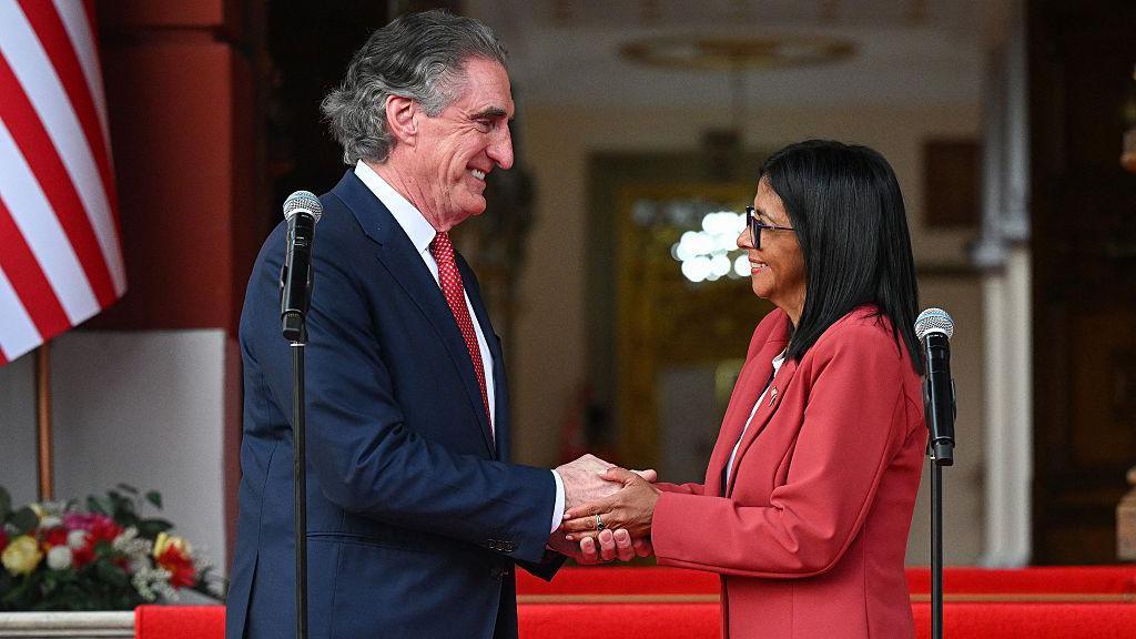 El secretario del Interior de Estados Unidos, Doug Burgum, y la presidenta encargada de la República Bolivariana de Venezuela, Delcy Rodríguez, mirándose de frente y dándose la mano el 5 de marzo de 2025 en el palacio de Miraflores, Caracas, Venezuela. (Foto: Federico PARRA / AFP vía Getty Images)