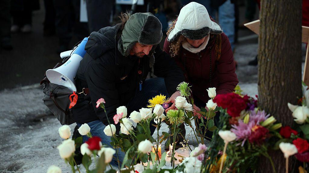 Un hombre y una mujer agachados colocan flores en honor a Renee Nicole Goods, quien falleció a tiros a manos de un agente federal durante una redada migratoria en Mineápolis, Minesota, Estados Unidos, el 7 de enero de 2026. (Foto: David Berding/Getty Images)