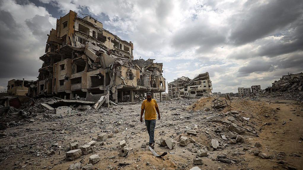 Una persona camina entre escombros de edificios en Gaza