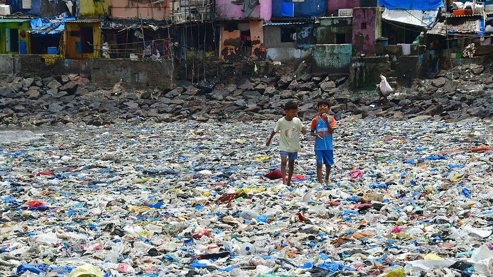 Niños caminando entre residuos plásticos
