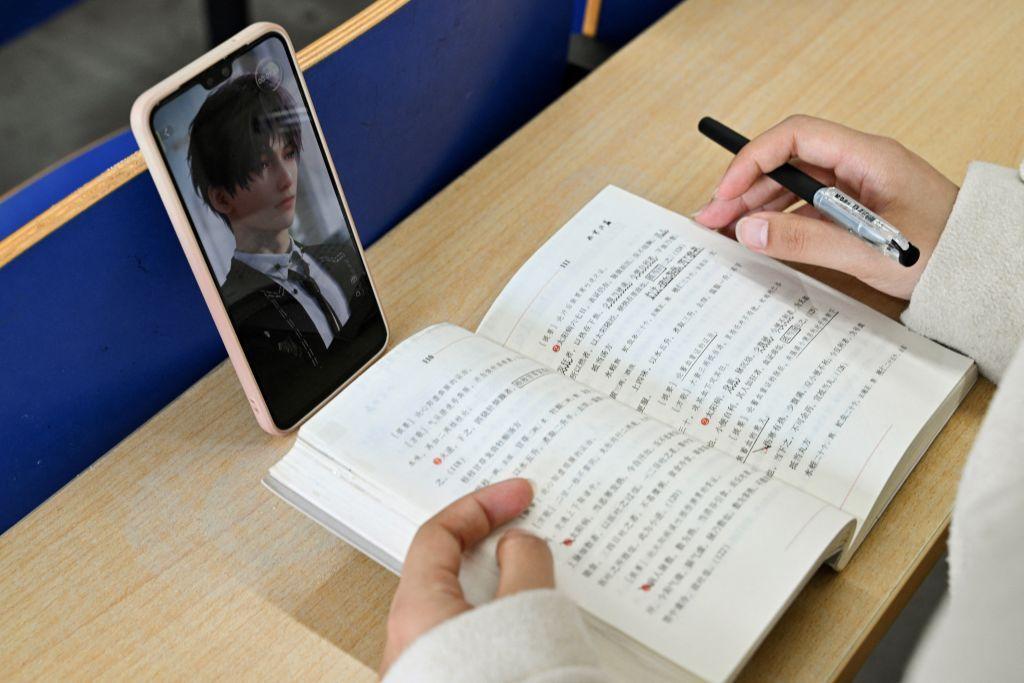 一本书前面摆着手机，手机上是一个游戏角色