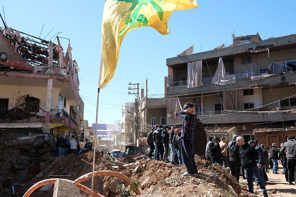 Esta fotografía, tomada durante una gira de prensa organizada por Hezbolá, muestra a un hombre instalando una bandera de Hezbolá en el balcón de un edificio dañado en la ciudad de Nabi Sheet tras una operación militar israelí en el valle de Bekaa, en Líbano, el 7 de marzo de 2026.
