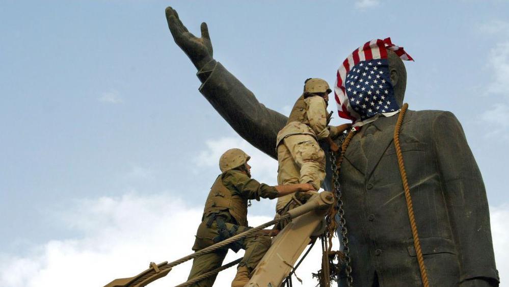 Soldados de EEUU colocan una bandera de su país a una estatua de Sadam Hussein en Irak en 2003.