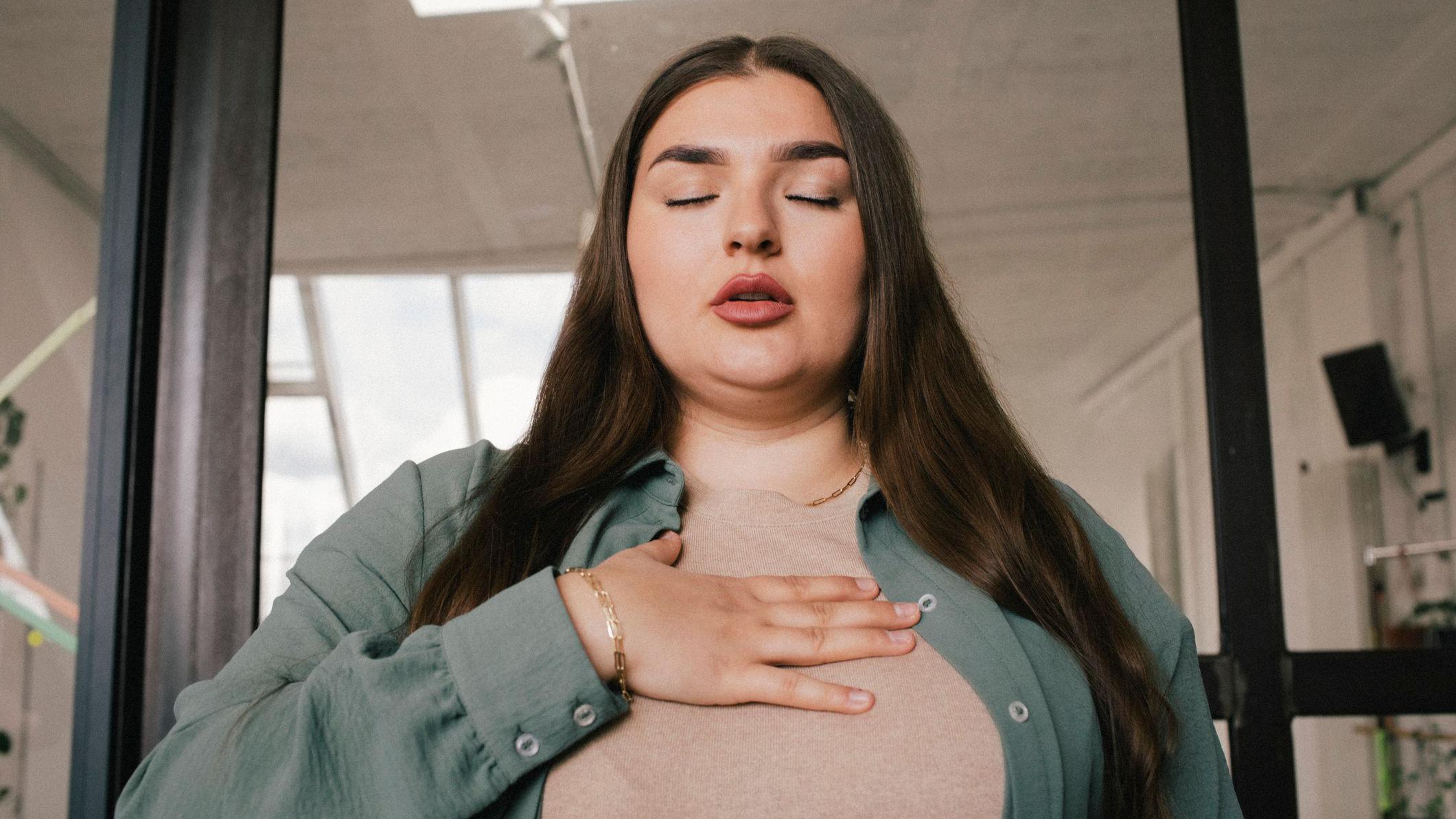 Una mujer con una mano a la altura de sus pulmones. 