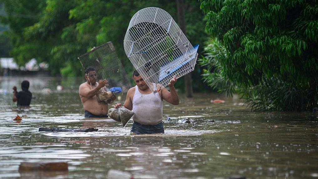 Hombre cargando una jaula, caminando por las calles inundadas de Poza Rica, en el estado de Veracruz