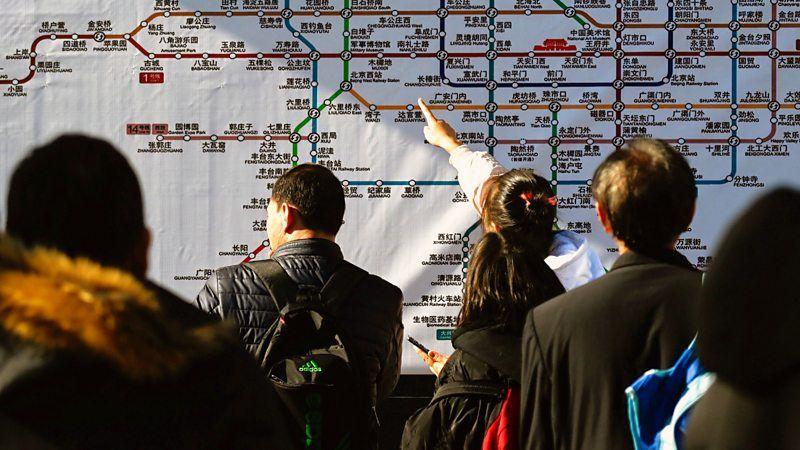 Pessoas observam e apontam para um mapa do metrô de Pequim, na China