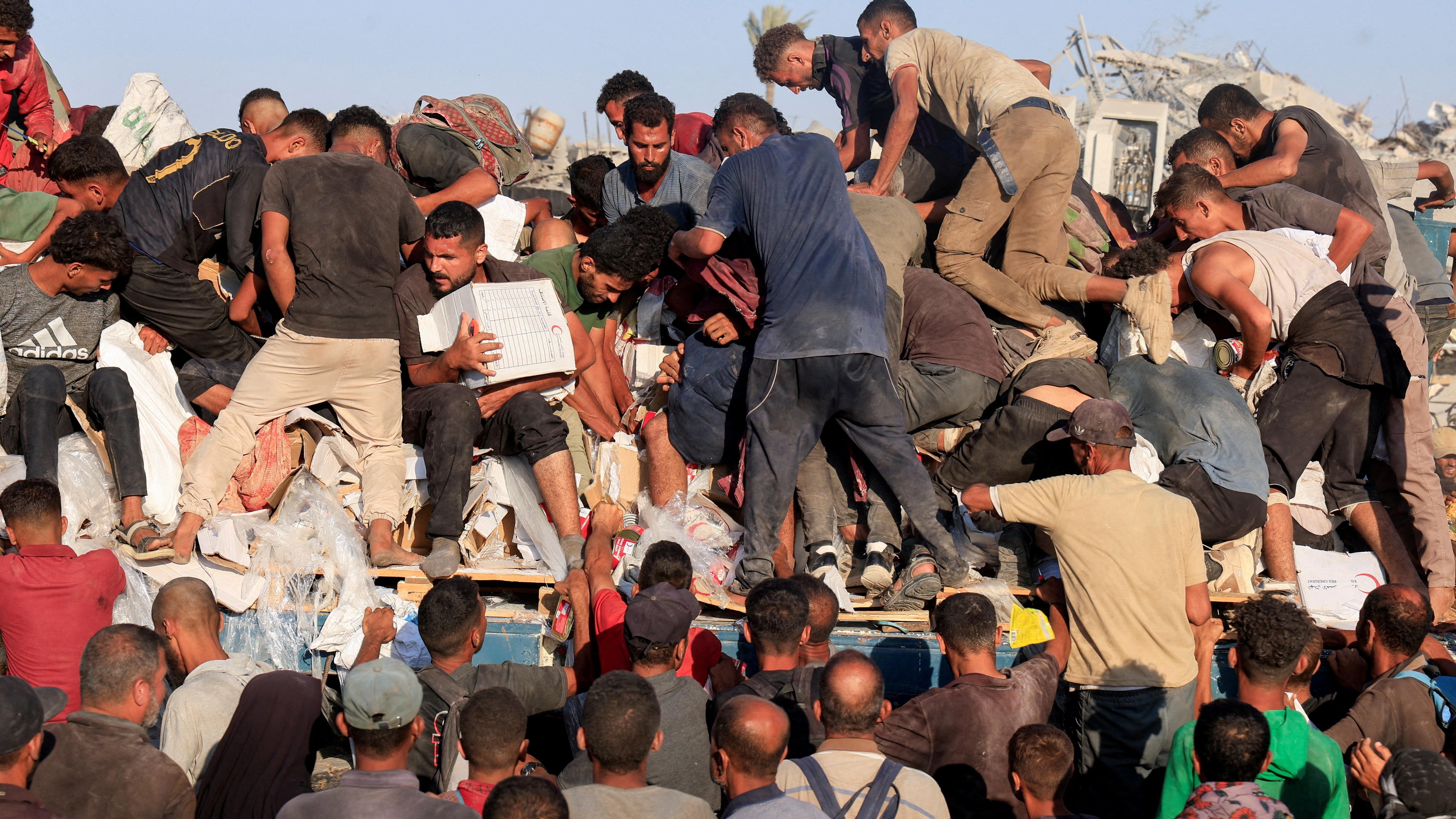 فلسطينيون يصعدون إلى شاحنة بحثًا عن مساعدات إنسانية في خان يونس