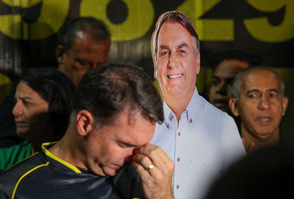 O senador brasileiro Flávio Bolsonaro, filho do ex-presidente Jair Bolsonaro, gesticula ao lado de um cartaz durante uma vigília pela sua saúde e liberdade em Brasília, em 22 de novembro de 2025. 