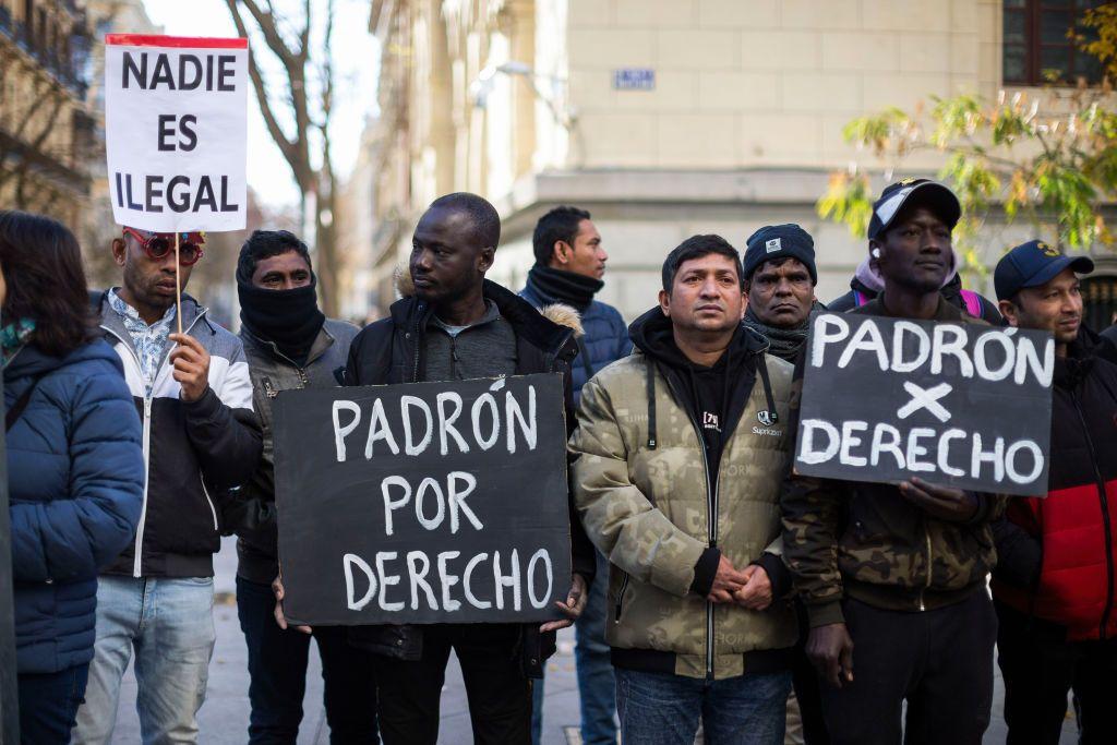 Dos inmigrantes sostienen carteles que dicen "Registro por derecho" en español, durante una manifestación frente al Ayuntamiento de Madrid.