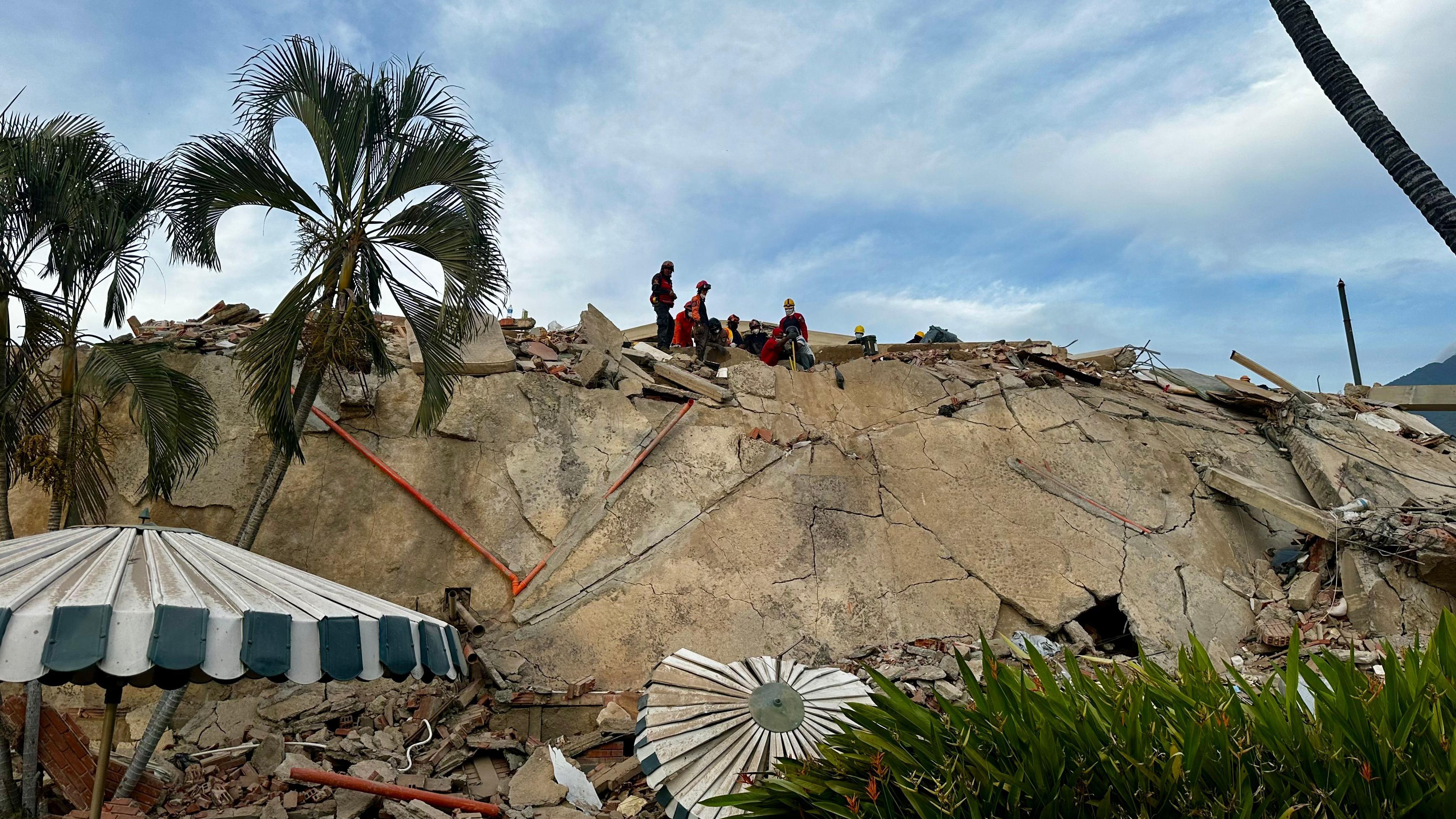 Escombros sobre el conjunto residencial Caribe, en la parroquia Caraballeda, estado La Guaira. En la cima de la pila de escombros se ve un pequeño grupo de rescatistas. 