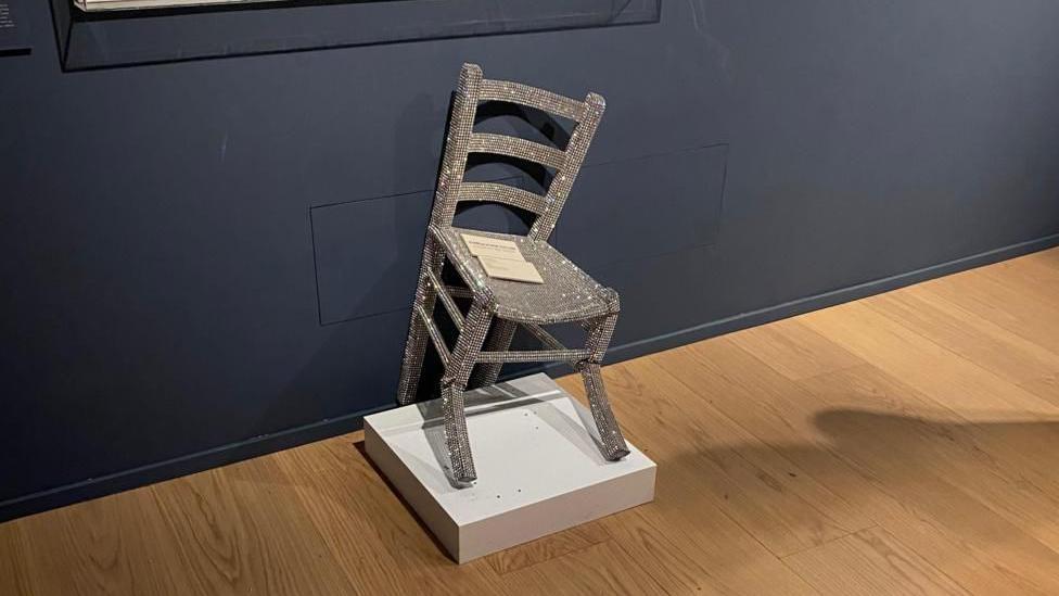 Una silla cubierta de cristales está rota en dos patas.