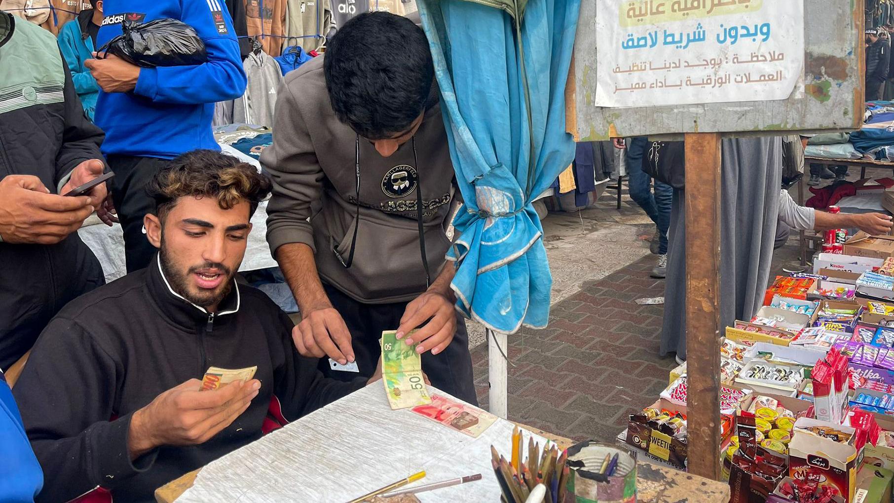 Baraa Abu al-Aoun repairing banknotes at a market in Gaza City