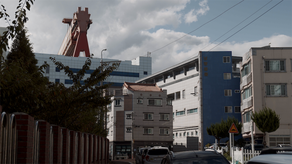 여러 채의 빌라 건물 뒤로 크레인이 보이는 사진