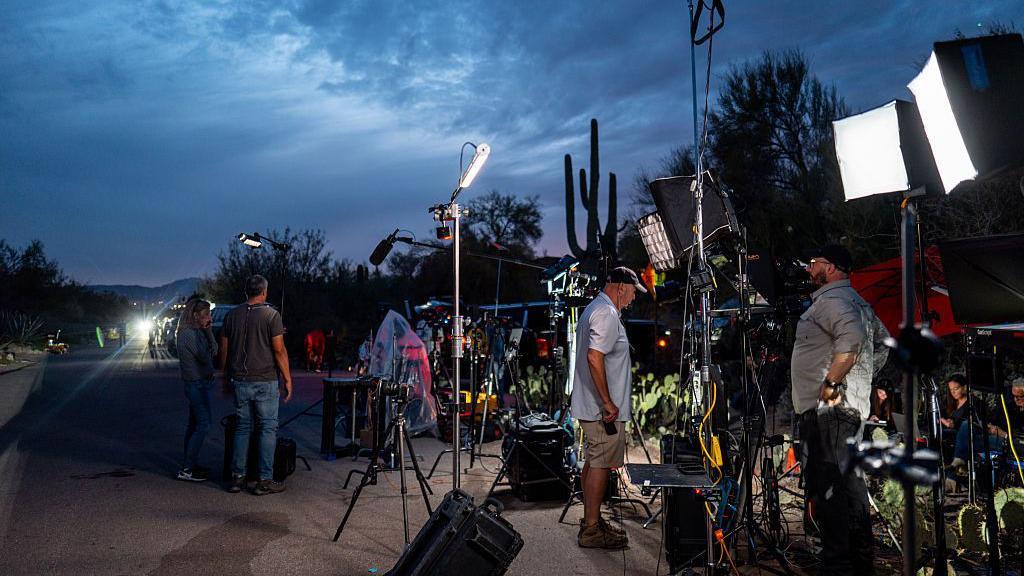 Los equipos de cámaras se instalan cerca de la casa de Nancy Guthrie, el cielo está oscuro y el sol casi se pone.
