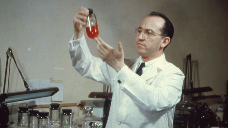 El dr. Salk con un frasco en la mano con una sustancia roja