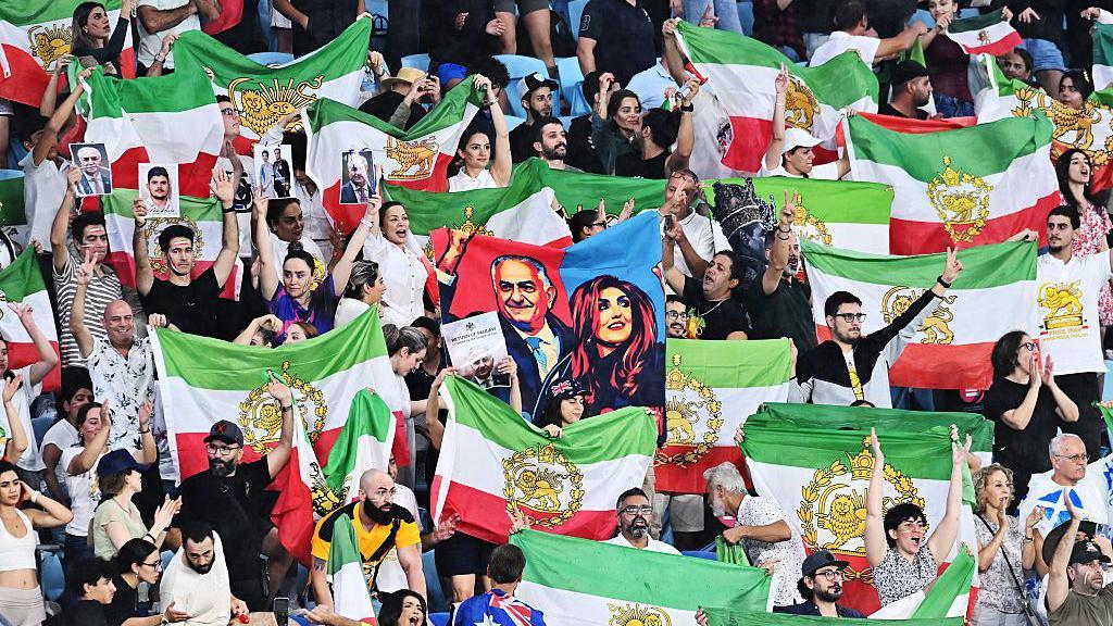 Iranski navijači na tribinama mašu zelenim, belim i crvenim zastavama
